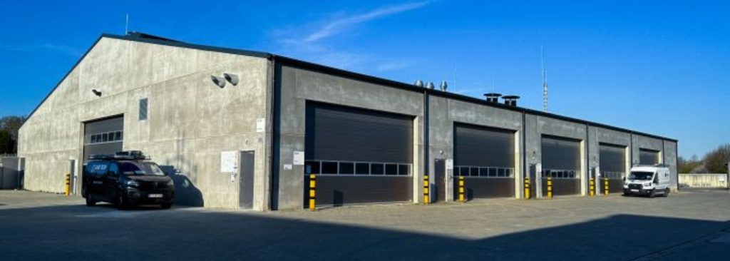 Buitenzicht van TRANSfarm KU Leuven met industriële hal en servicevoertuigen van Bumaco Group.