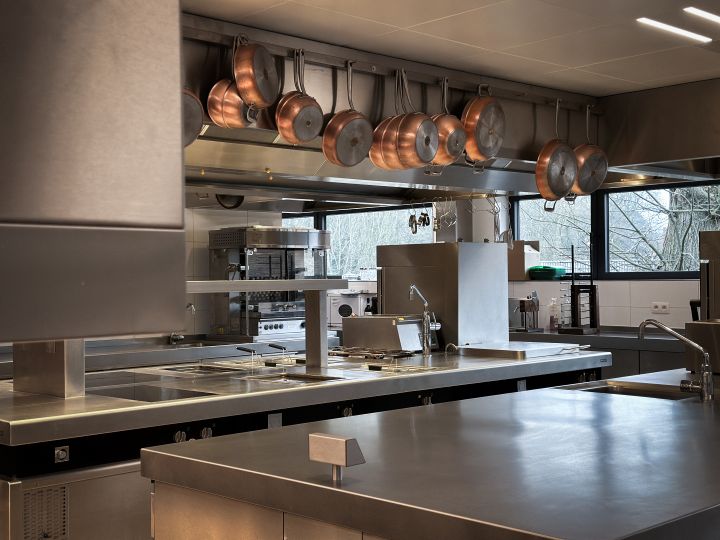 Centrale werktafel en dampkap met logo in de professionele keuken van Maison Colette.