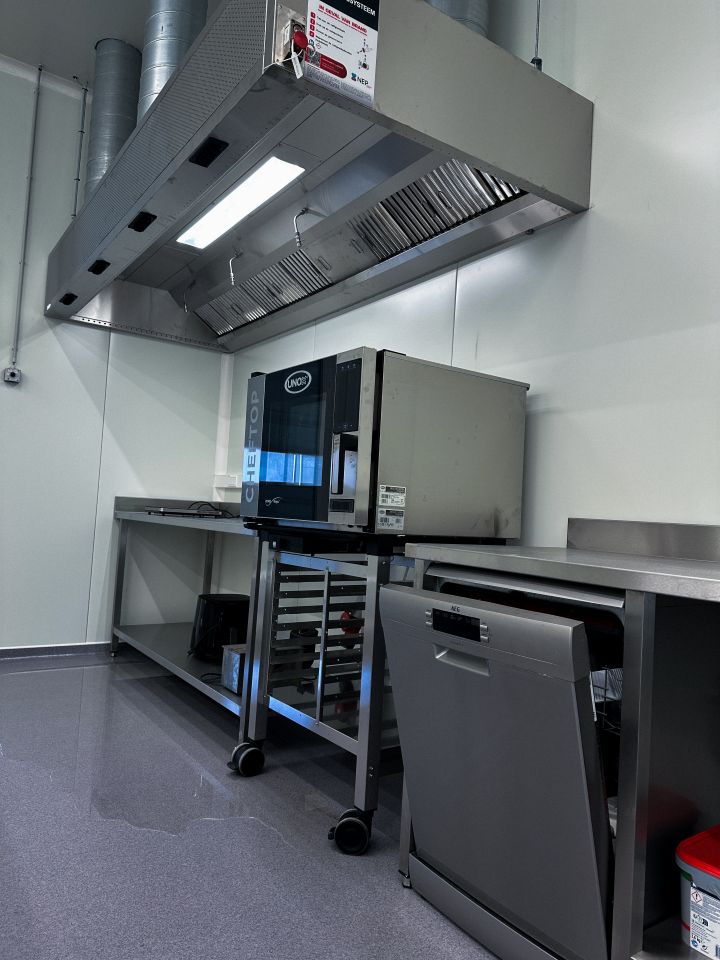 Keukenruimte van TRANSfarm KU Leuven met Unox Cheftop, dampkap, inox werkblad en vaatwaszone.
