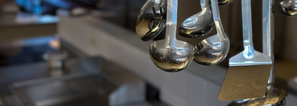 Hangende kookgerei aan de kookline in de keuken van MRS Tubize